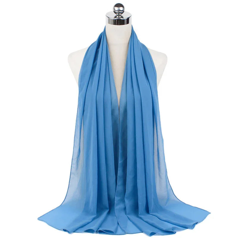 Light blue chiffon scarf draped on white mannequin with silver top against white background