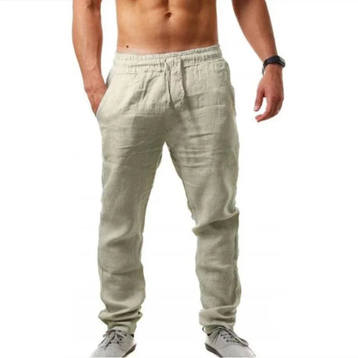 Men's beige linen casual pants with elastic waist and side pockets, styled with gray sneakers