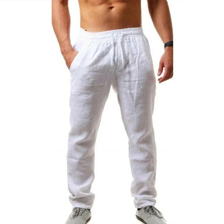 Man wearing white linen pants with elastic waistband and pockets, paired with gray casual shoes