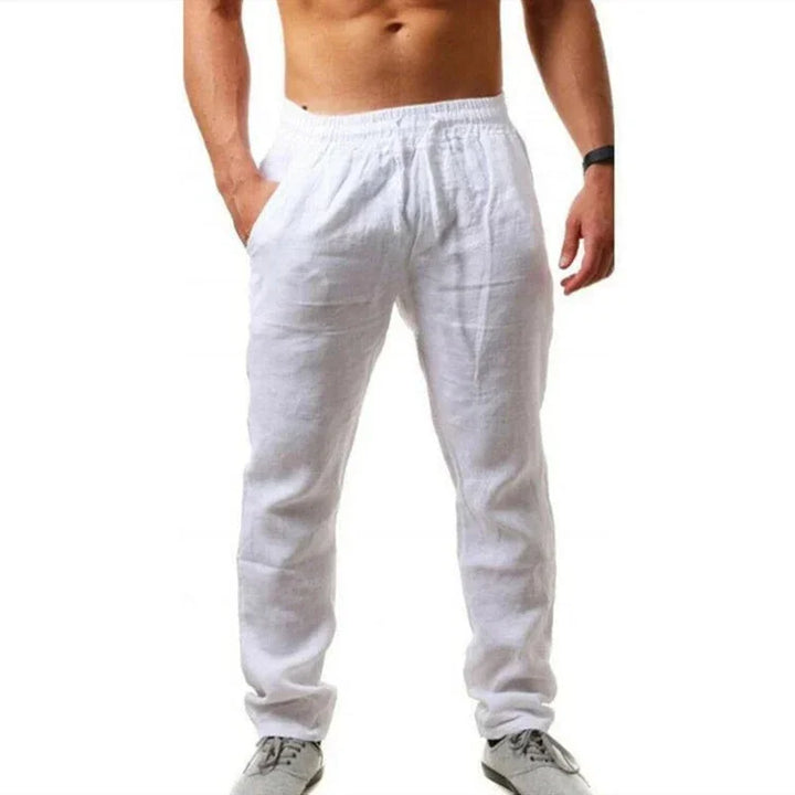 Man wearing white linen pants with elastic waistband and pockets, paired with gray casual shoes