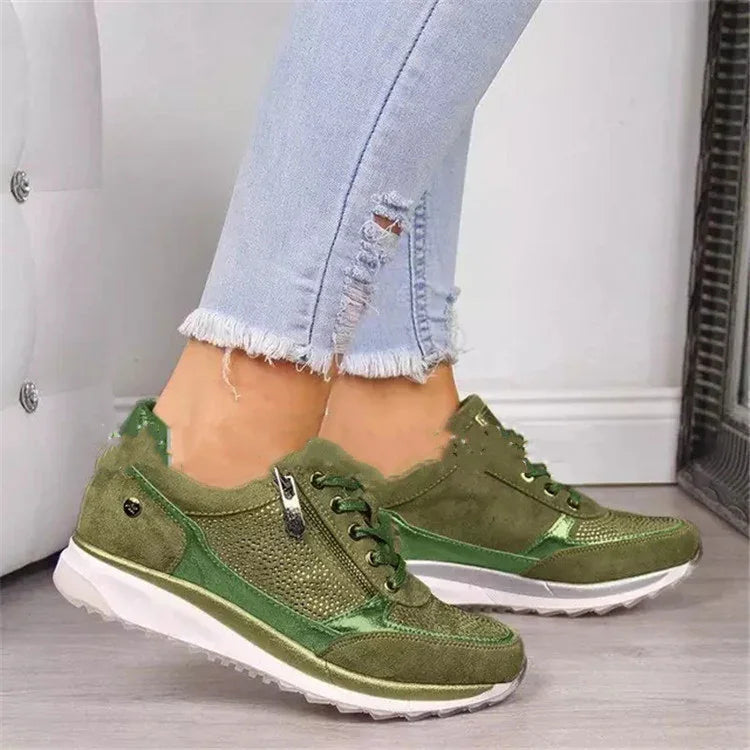 Green suede sneakers with mesh details, zippers, and white soles worn with light blue ripped jeans