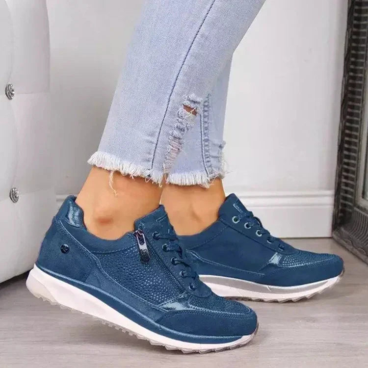 Blue casual sneakers with white soles worn with light blue frayed hem jeans on wooden floor