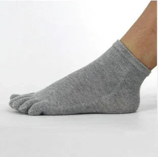 Close-up of a foot wearing gray toe socks on a white background