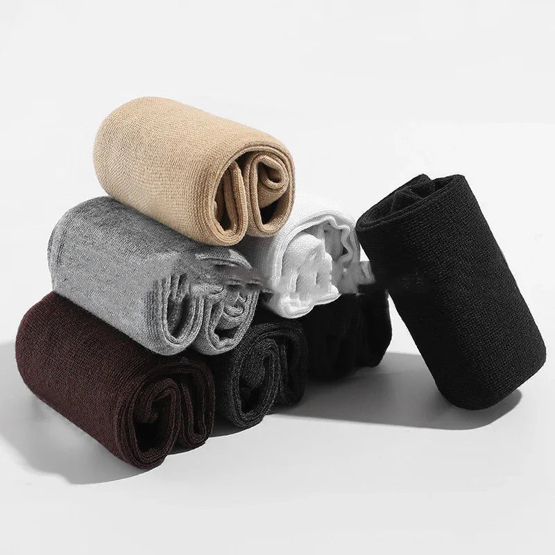 Stack of rolled cotton socks in beige, gray, white, black, and brown on white background