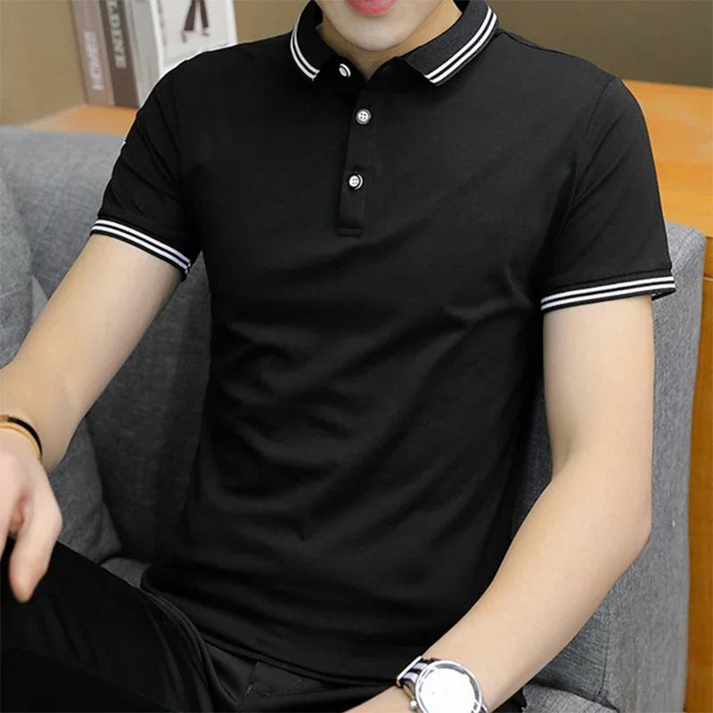 Man wearing black polo shirt with white double stripes on collar and sleeves sitting on gray sofa
