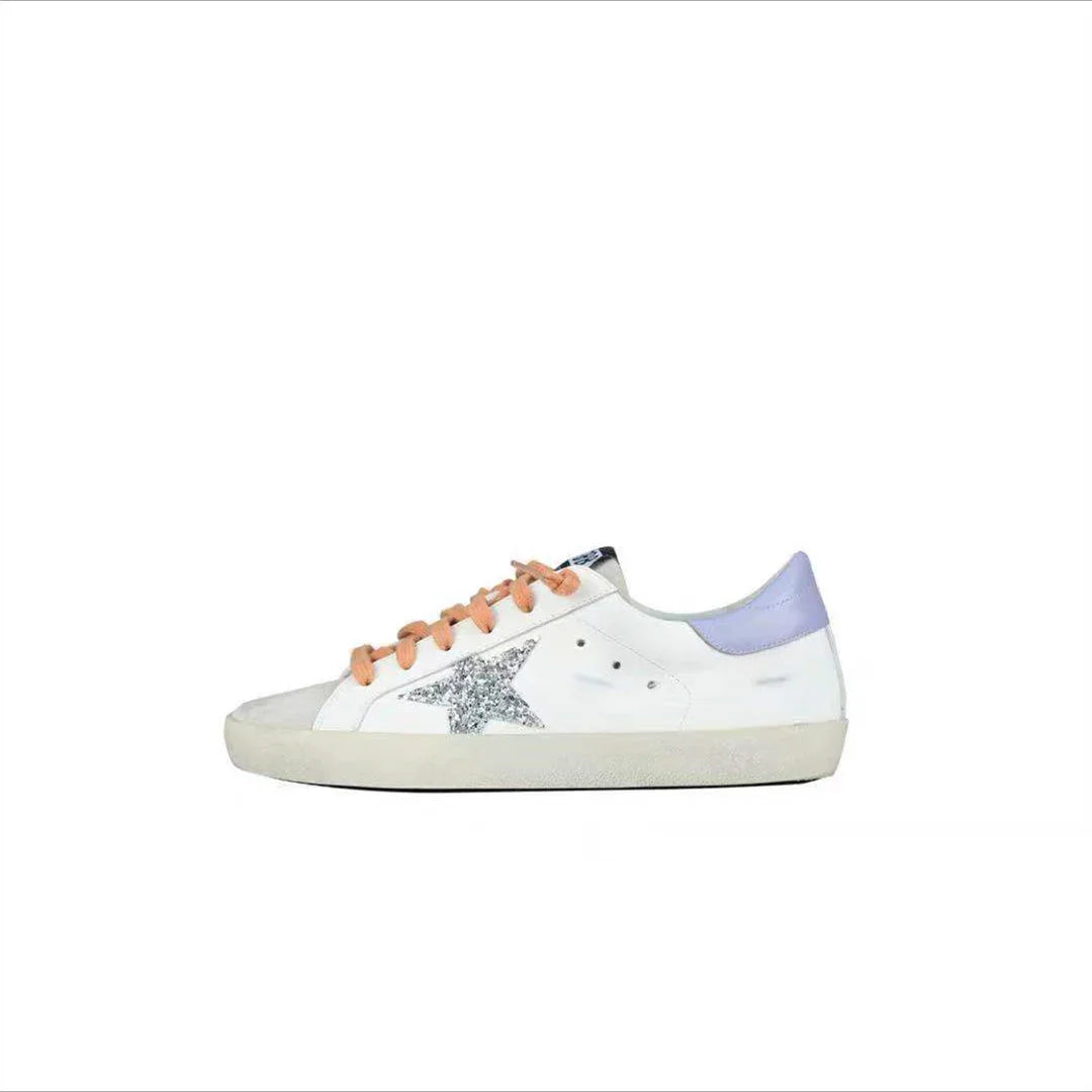 White low-top sneaker with glitter silver star, lavender heel tab, and peach laces on white background