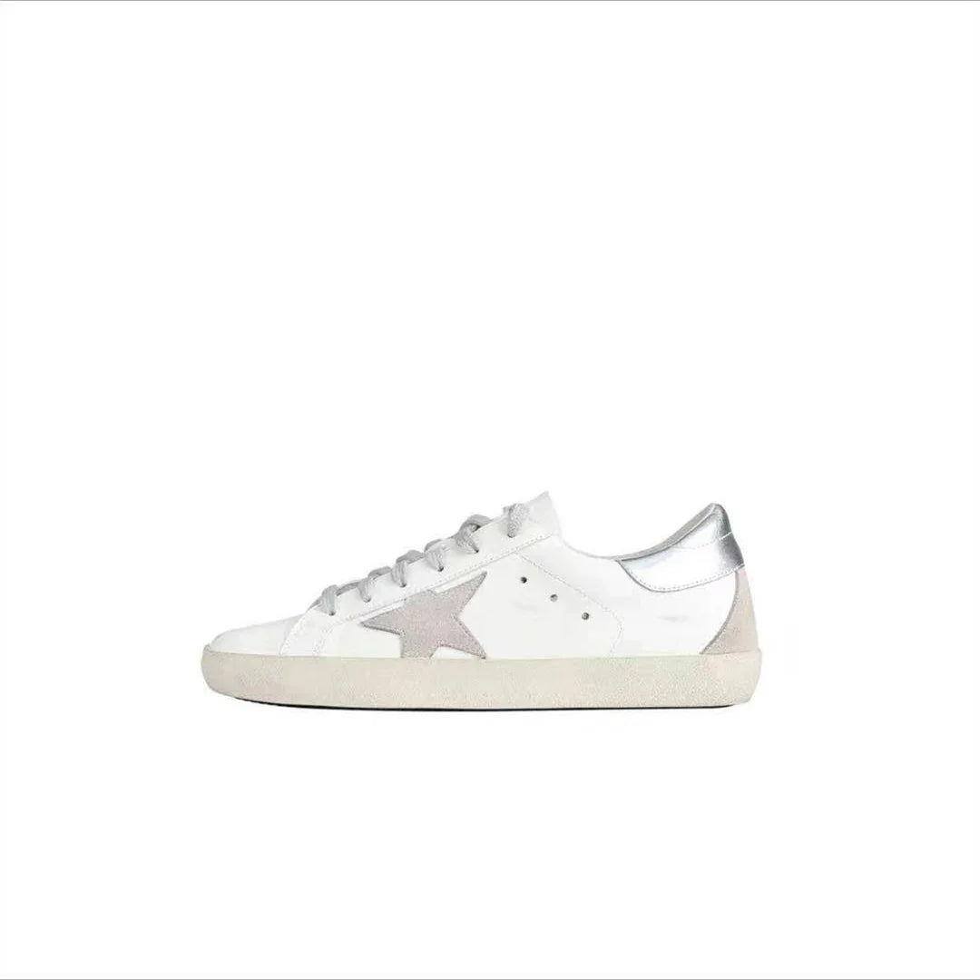 White low-top sneaker with silver star logo and metallic silver heel tab on white background