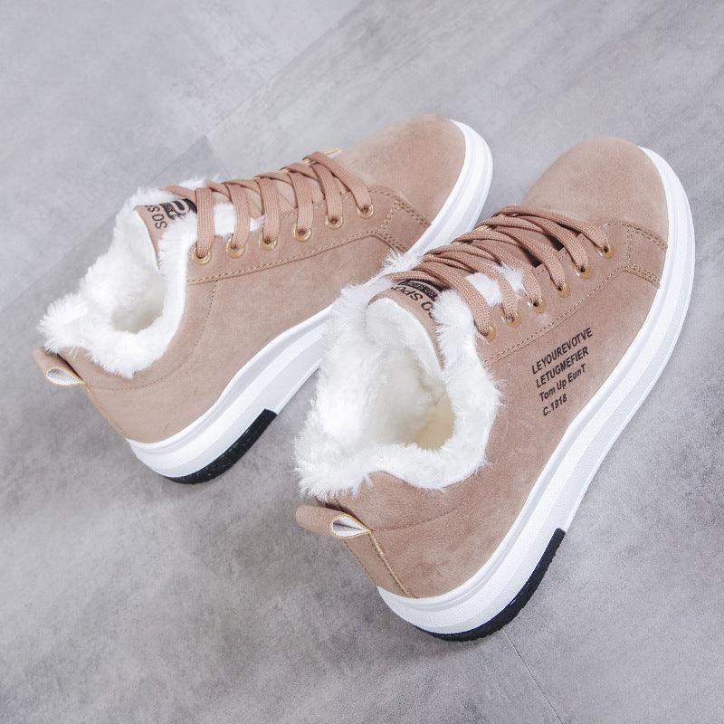 Beige suede sneakers with white fur lining and white rubber soles on grey floor
