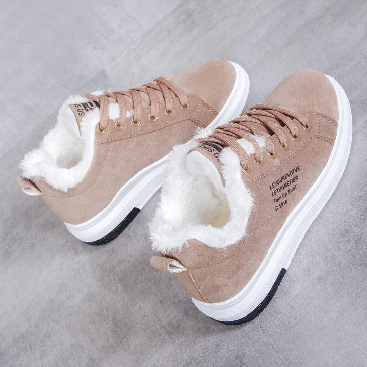 Beige suede sneakers with white fur lining and white rubber soles on grey floor