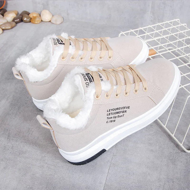 Beige high-top sneakers with white faux fur lining and beige laces on gray floor with pebbles