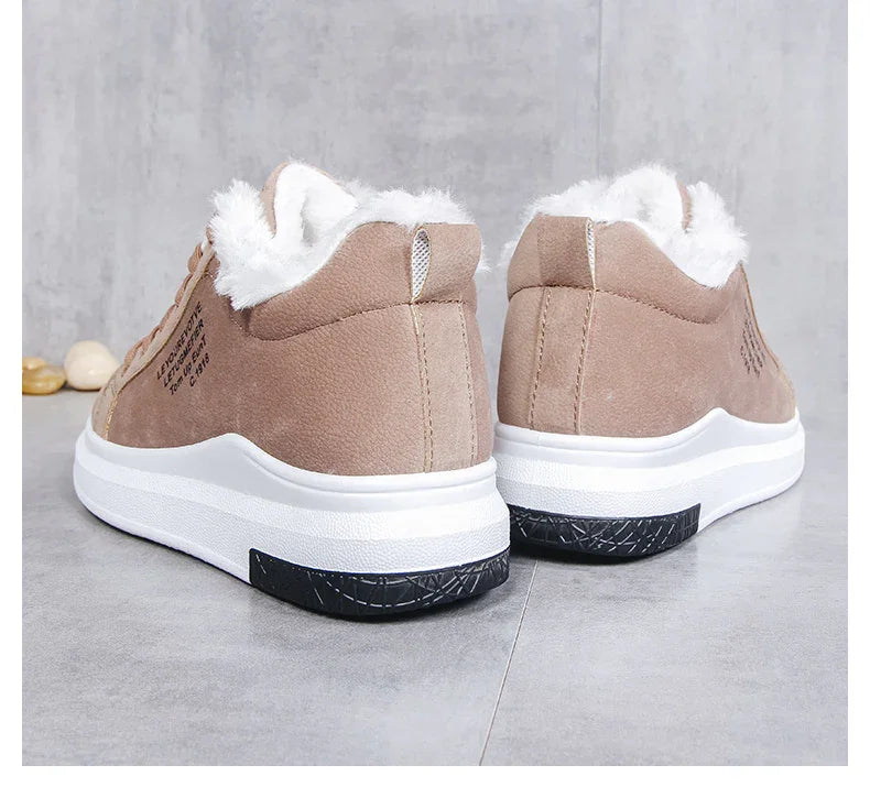 Beige suede sneakers with white fur lining and thick white and black soles on gray surface