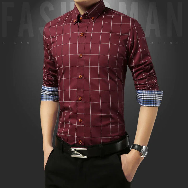 Man wearing fitted maroon checkered shirt with rolled blue plaid cuffs, black pants, and watch