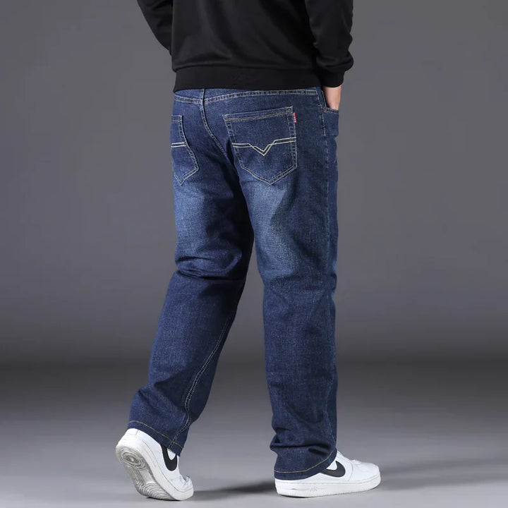Rear view of person wearing dark blue denim jeans and white Nike sneakers on gray background