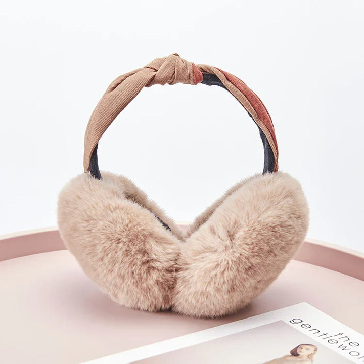 Soft beige faux fur earmuffs with a knotted fabric headband on a pink surface