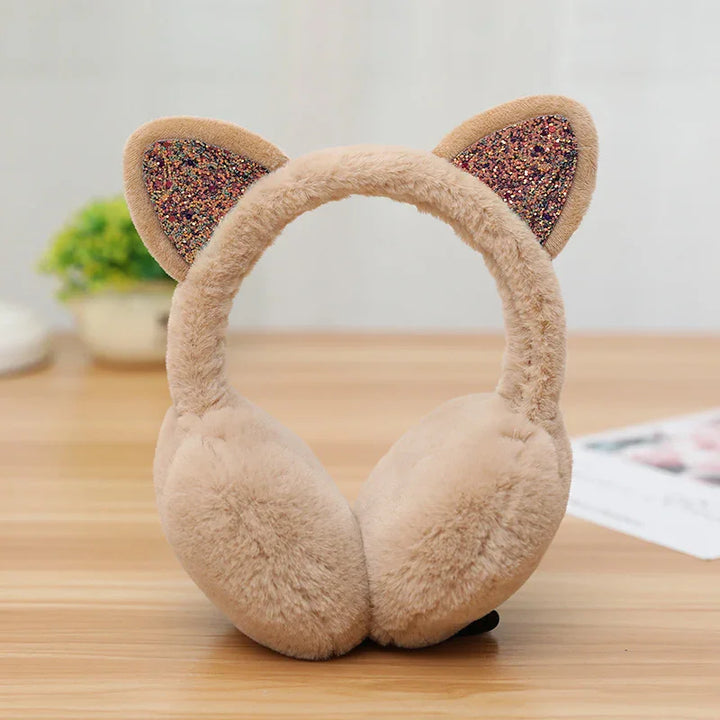 Beige fluffy earmuffs with glittery cat ears on wooden surface with blurred background