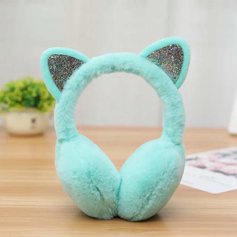 Light blue fluffy earmuffs with glittery cat ears on wooden table indoors