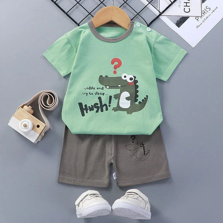 Kids green t-shirt with cartoon crocodile and text, paired with gray shorts and white sneakers