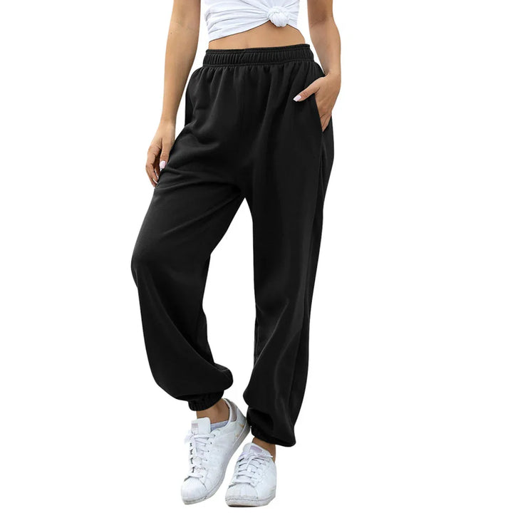 Woman wearing black jogger pants with elastic waist and cuffs, paired with white sneakers and cropped top