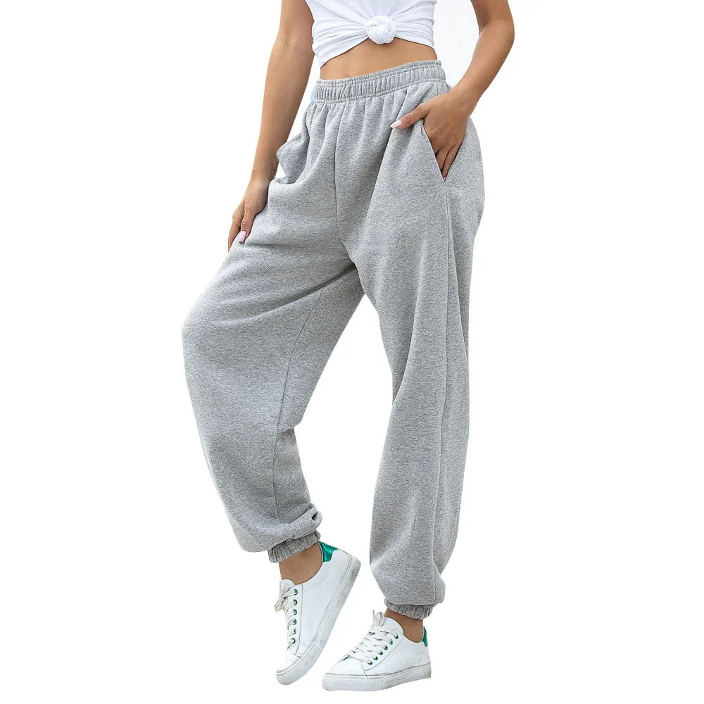 Woman wearing gray loose-fit sweatpants with elastic cuffs and white sneakers with green accents