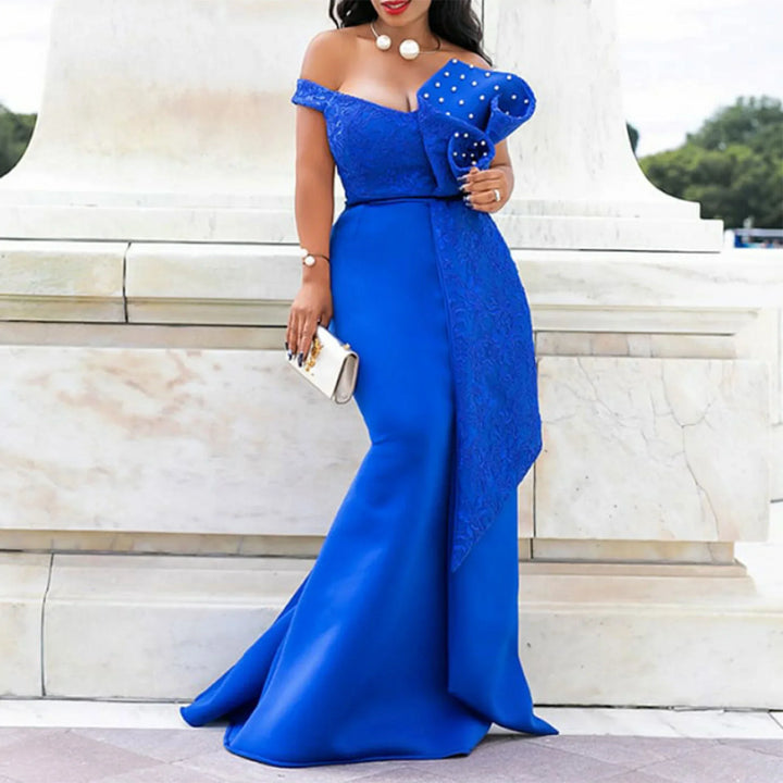 Woman in elegant royal blue off-shoulder evening gown with pearl details, holding clutch outdoors