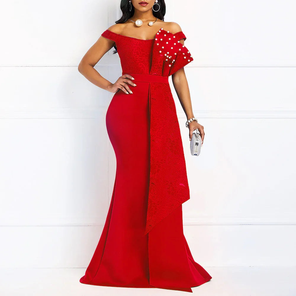 Woman in elegant red off-shoulder evening gown with bow and pearl details holding a silver clutch