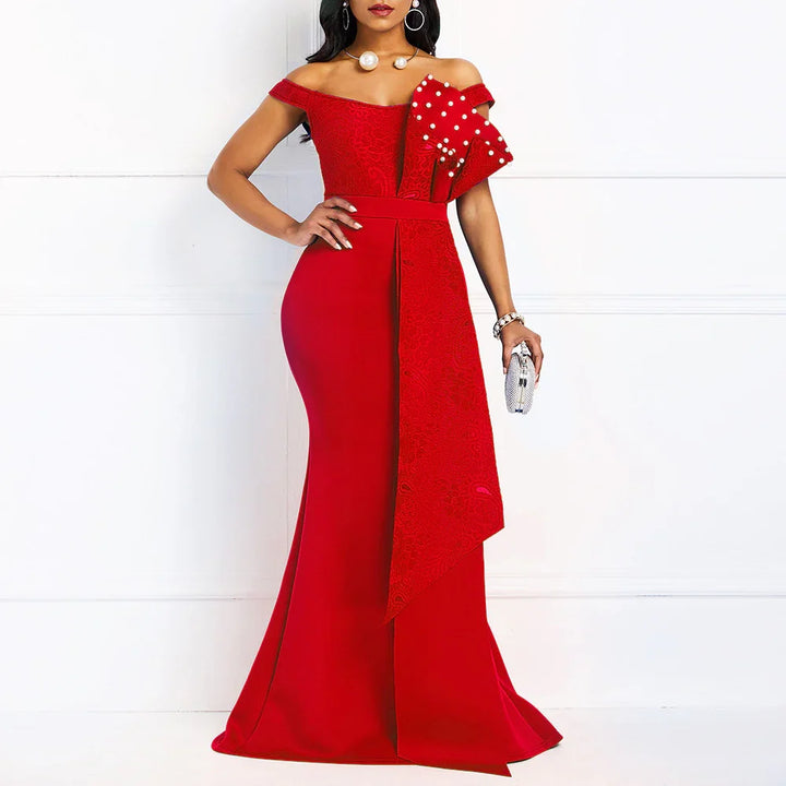 Woman in elegant red off-shoulder evening gown with bow and pearl details holding a silver clutch