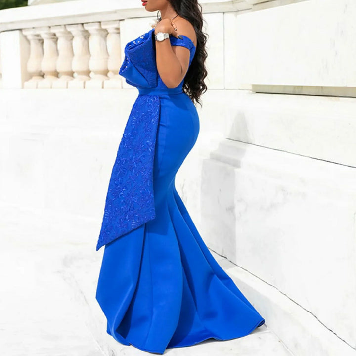 Woman in elegant royal blue off-shoulder evening gown with embellished overlay, outdoors