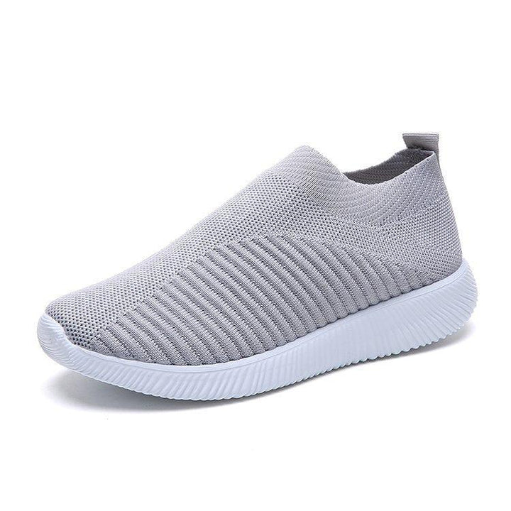 Light gray slip-on knit sneaker with white textured sole, breathable casual shoe design
