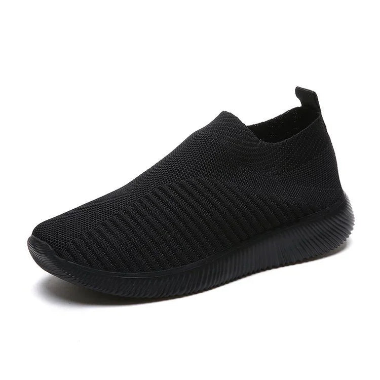 Black knit slip-on sneaker with textured sole and pull tab on white background