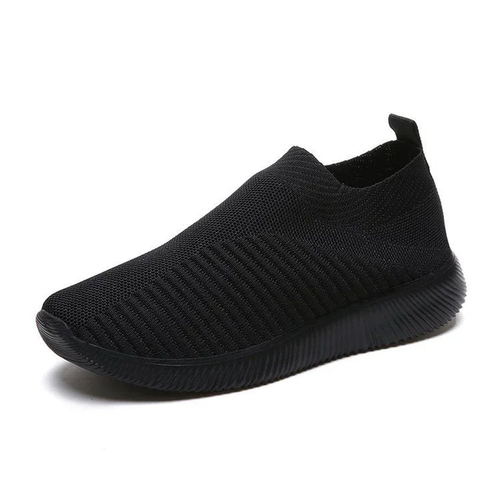 Black knit slip-on sneaker with textured sole and pull tab on white background