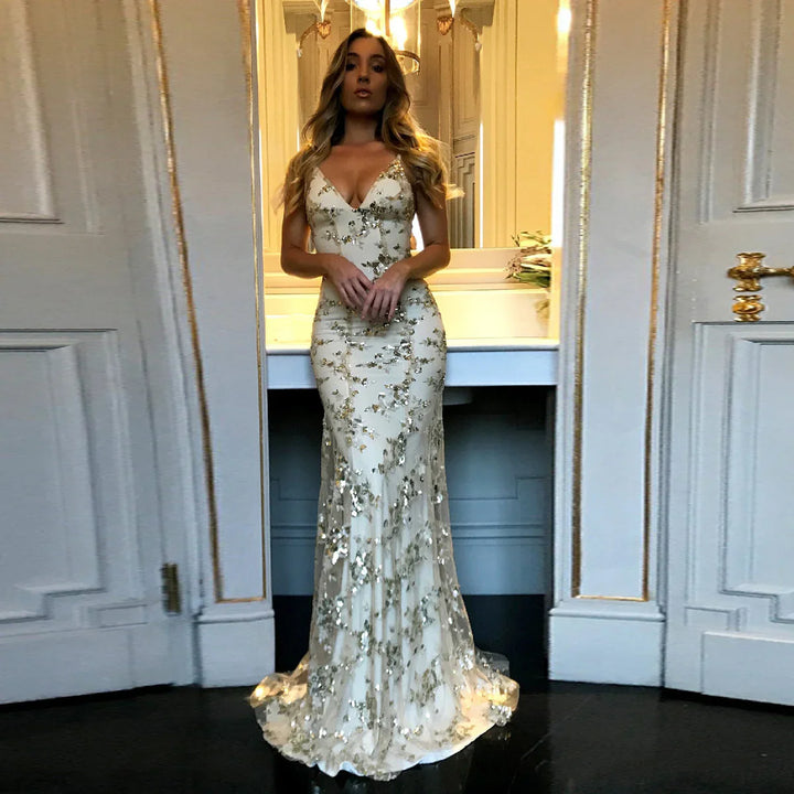Woman in a white and gold sequin evening gown standing in a luxurious room with ornate white and gold doors
