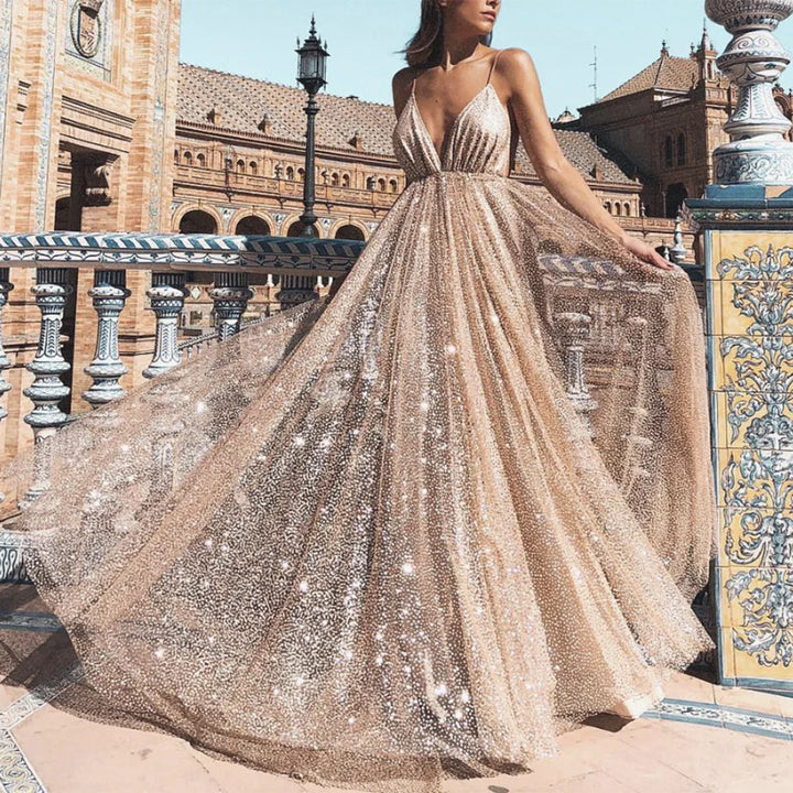 Woman in sparkling champagne tulle gown with deep V-neck standing on ornate tiled balcony