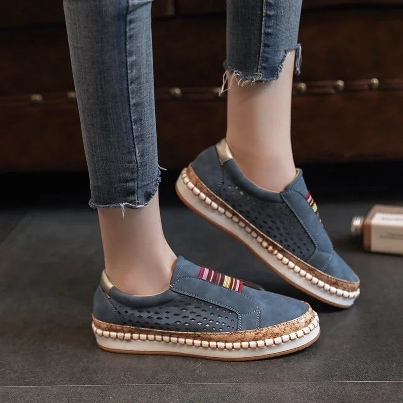 Casual blue slip-on sneakers with perforated sides and colorful striped detail worn with frayed hem jeans