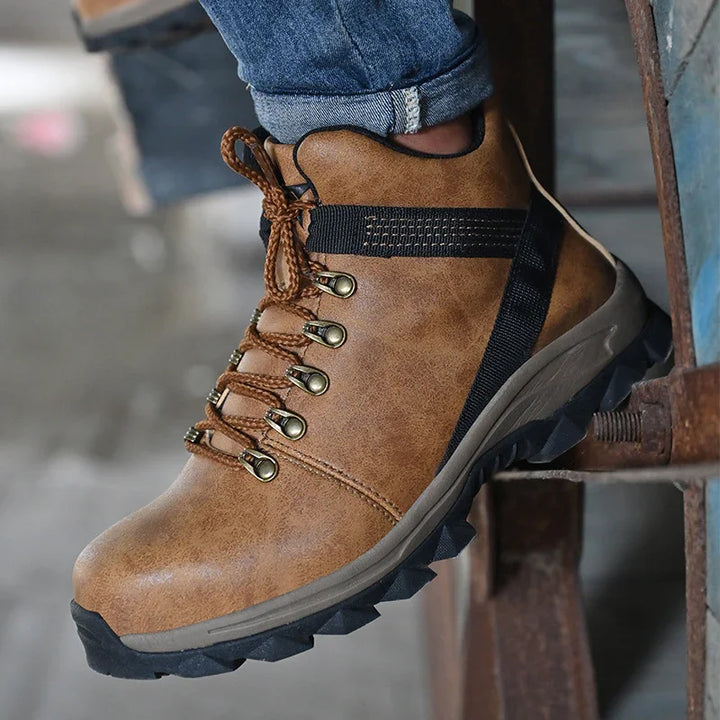 Close-up of brown hiking boot with black sole and metal eyelets worn with blue jeans on rustic metal structure