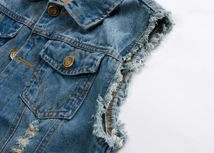 Close-up of a blue distressed denim vest with frayed armholes and brass buttons on white background