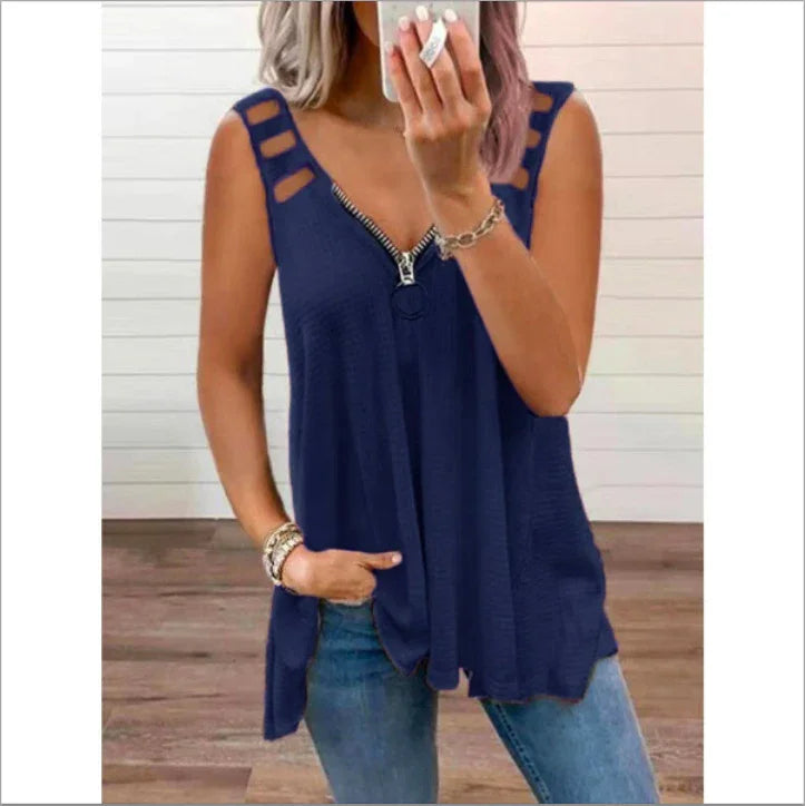 Woman wearing navy blue sleeveless top with zipper detail and cutout straps paired with blue jeans