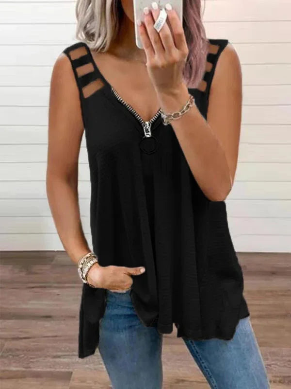 Woman wearing black sleeveless top with zipper front and striped shoulder straps, paired with blue jeans