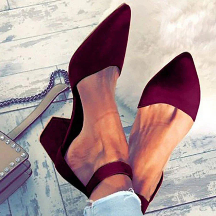 Woman wearing stylish burgundy pointed toe ankle strap block heels on wooden floor