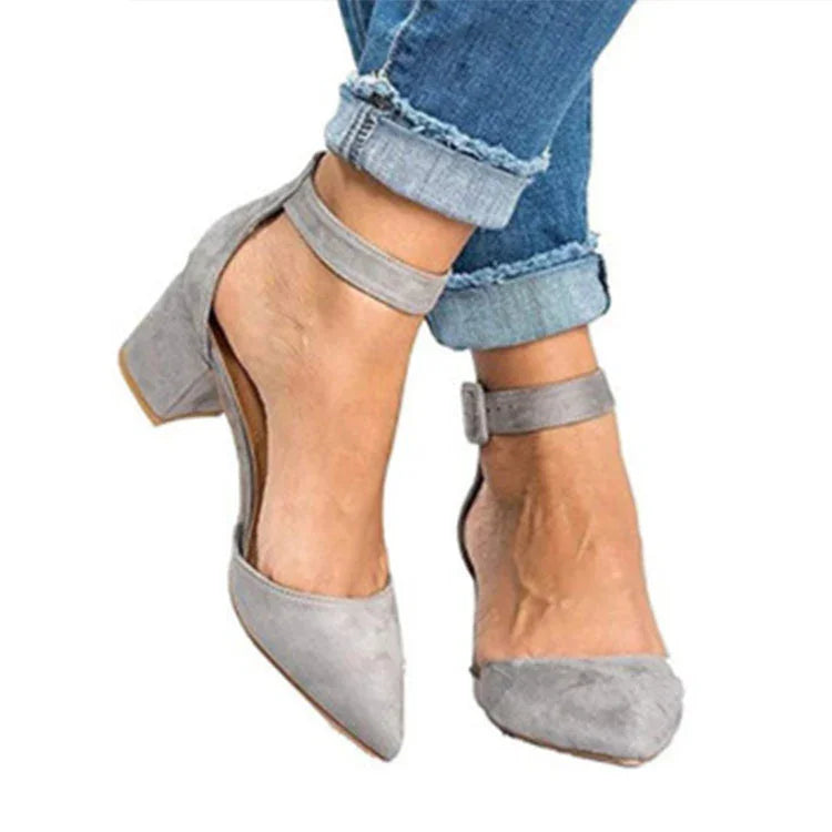 Woman wearing light gray suede ankle-strap block heels paired with rolled-up blue jeans