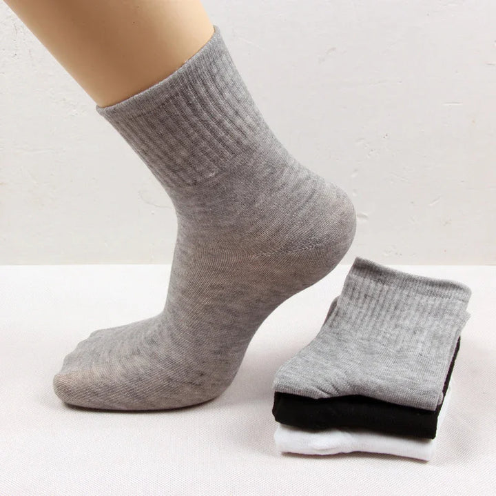 Footwear mannequin wearing a grey ribbed crew sock with three folded socks in grey, black, and white beside it