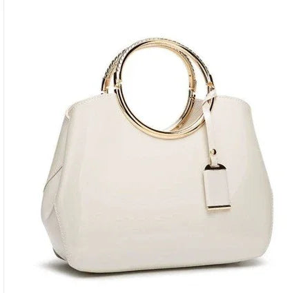Elegant white handbag with gold metal round handles and a hanging tag on white background