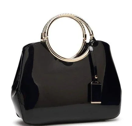 Elegant black patent leather handbag with shiny gold circular handles and hanging tag