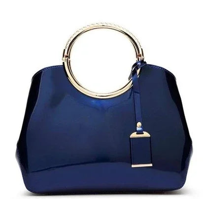 Elegant navy blue handbag with shiny gold circular handle and decorative tag