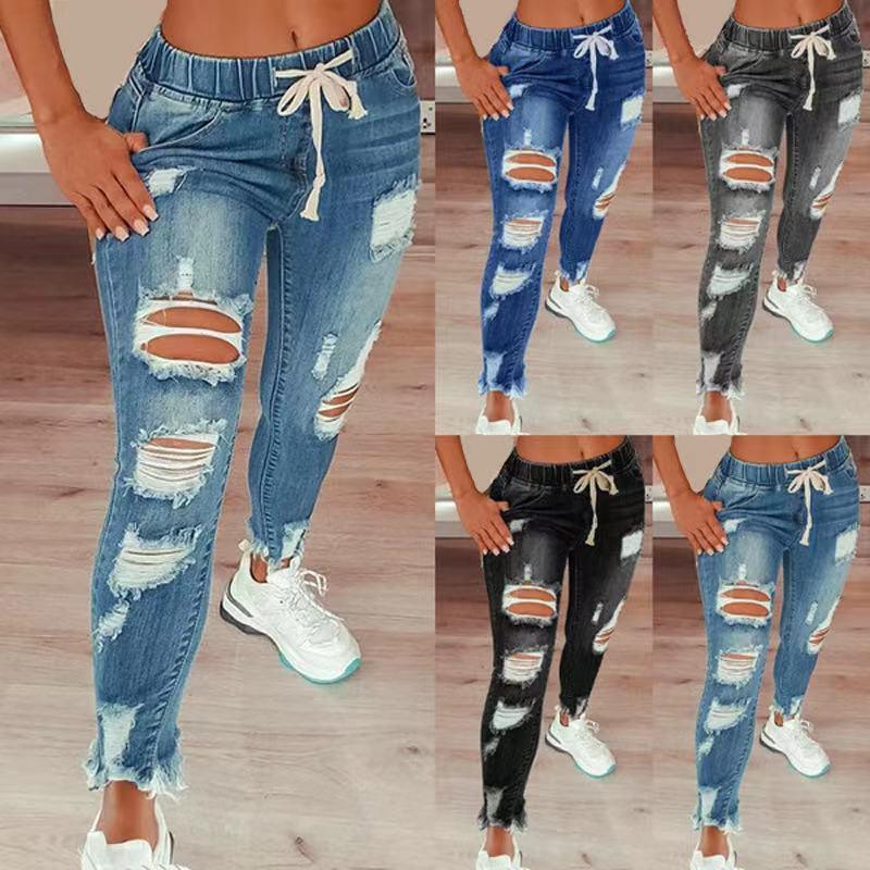 Women wearing ripped high-waist denim joggers with drawstring waist, styled with white sneakers