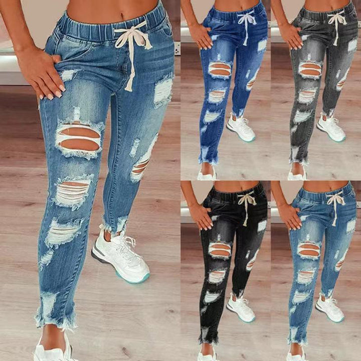 Women wearing ripped high-waist denim joggers with drawstring waist, styled with white sneakers