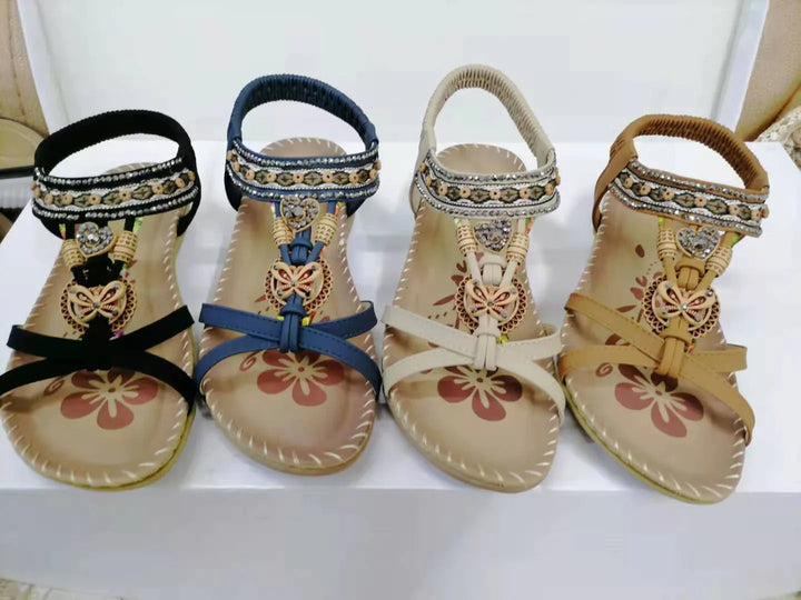 Four pairs of women’s decorated sandals in black, blue, beige, and brown with floral patterns and butterfly charms