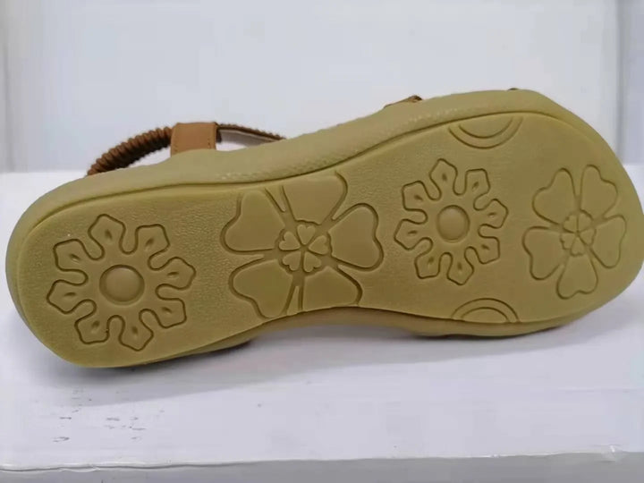 Brown sandal sole with flower-shaped tread pattern on white surface