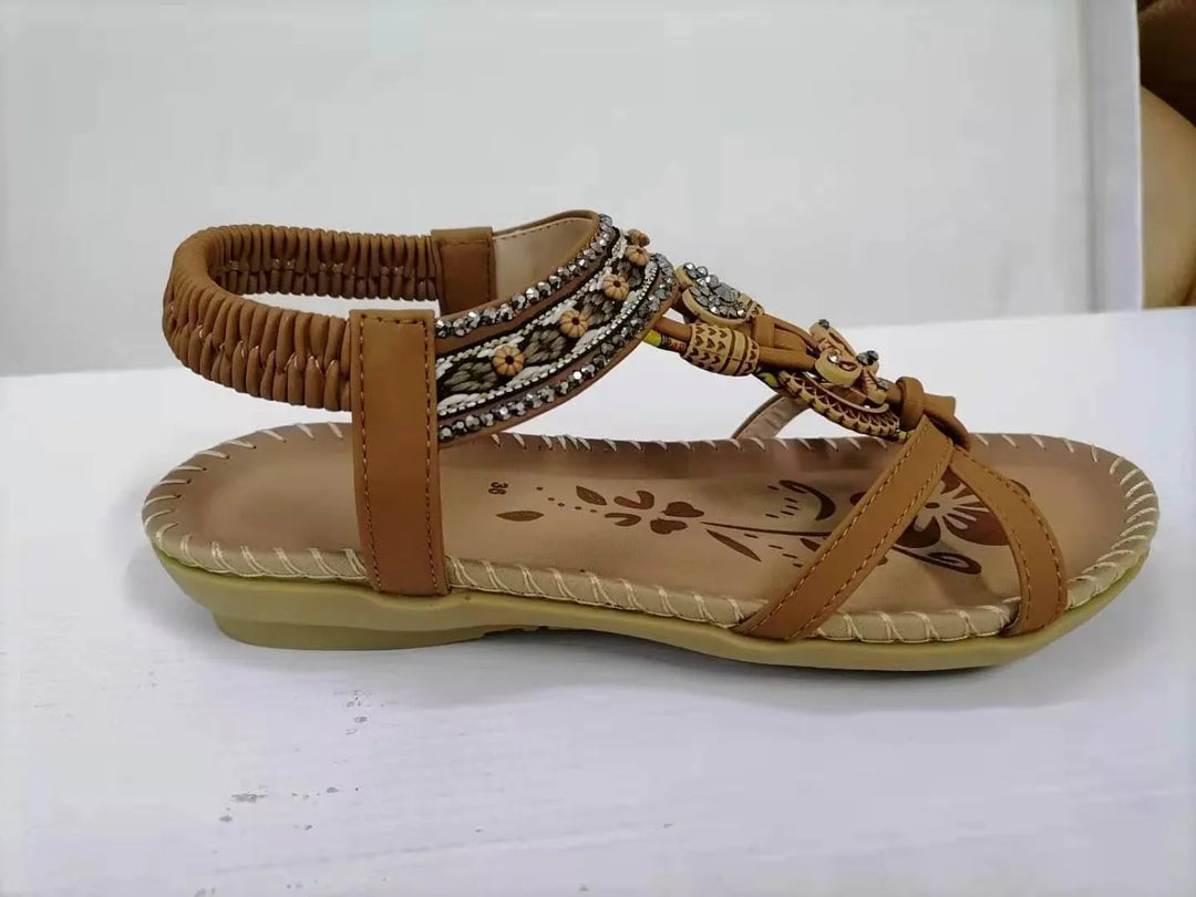 Brown women's sandal with woven ankle strap, floral embroidery, and decorative beads on a white surface