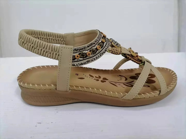 Beige women's sandal with decorative beads, elastic back strap, and floral print footbed