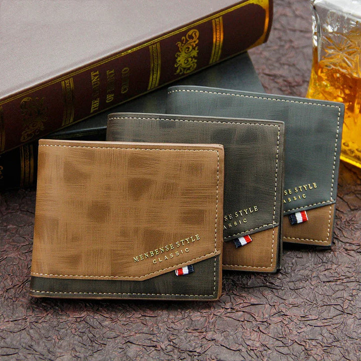Three classic men's bifold wallets in brown and gray leather with stitching and label on textured surface